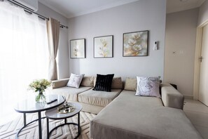 A modern living room with a sofa set, a coffee table, and wall art. - Smart Home, Breakfast, Starlink WiFi, Pool, Secure, close to airport (Gaborone)