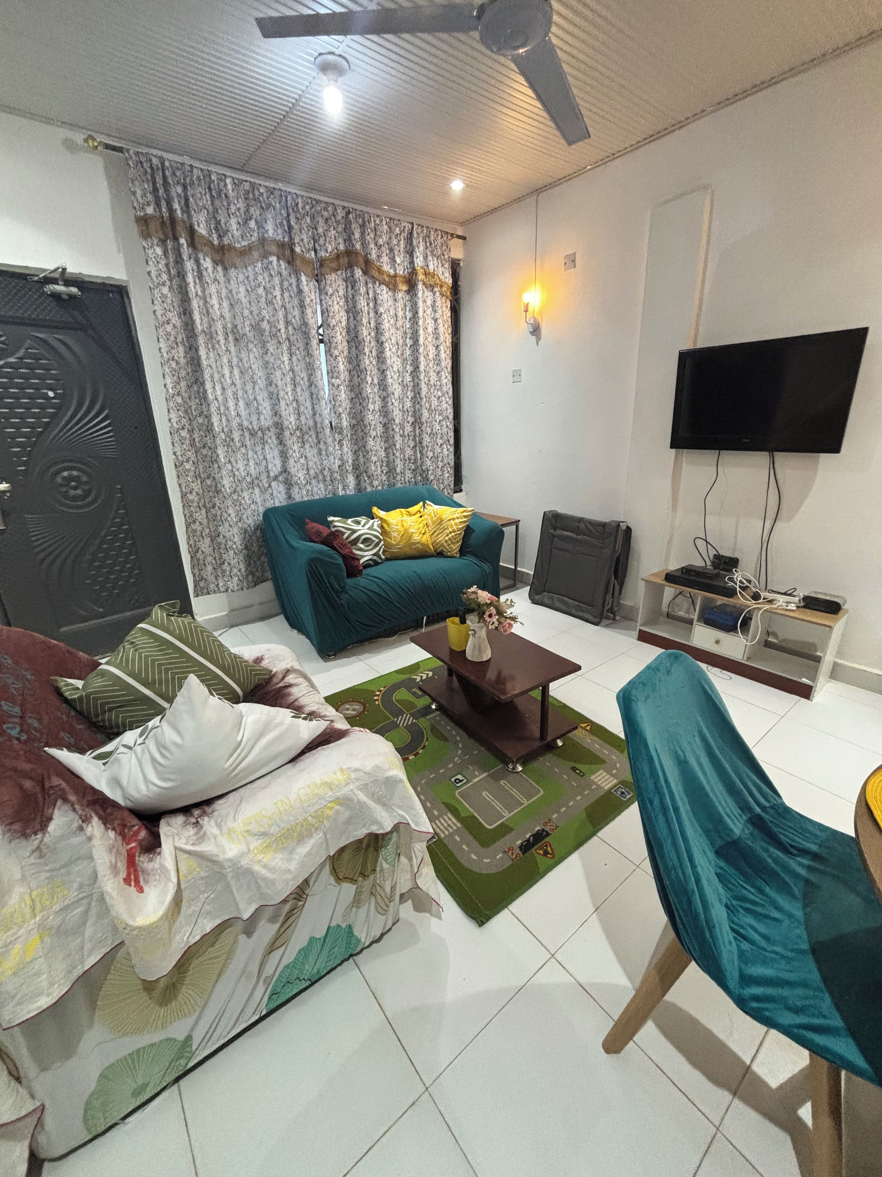 A living room with a sofa, a chair, a coffee table, a television, and a decorative wall light.
