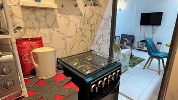 A kitchen with a gas stove, a coffee maker, and a red fire blanket on the counter.