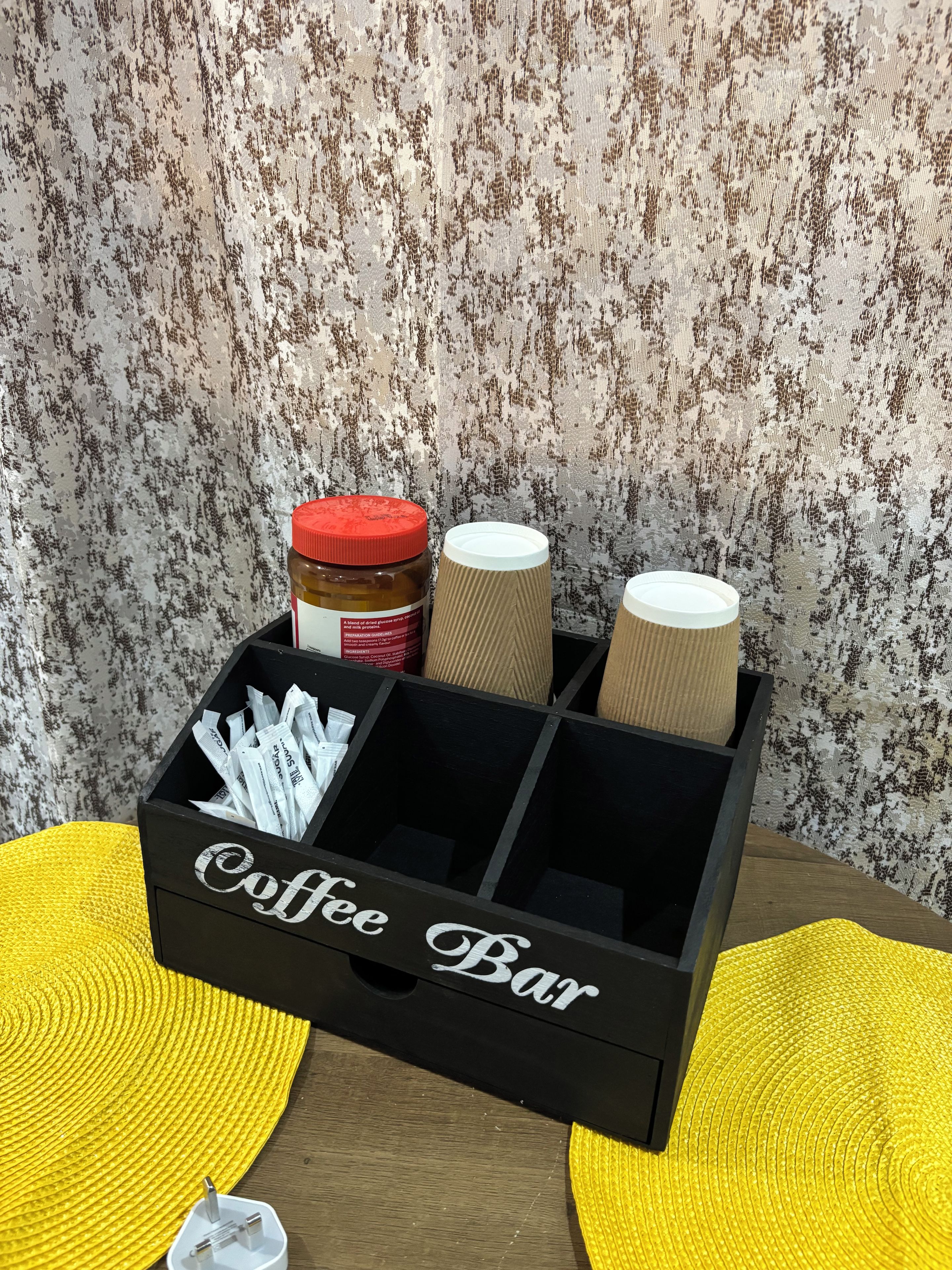 A coffee bar setup with a jar of honey, a container of sugar, and a creamer.