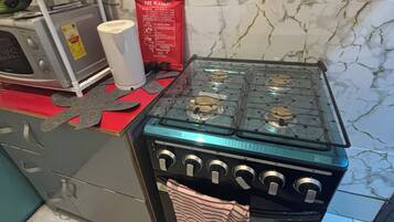 A kitchen with a gas stove, a microwave, and a red fire blanket on the counter.