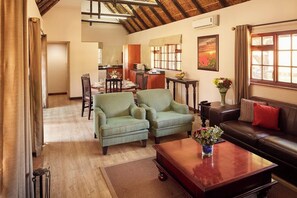 A living room with a sofa, two armchairs, a coffee table, and a dining area with a table and chairs.