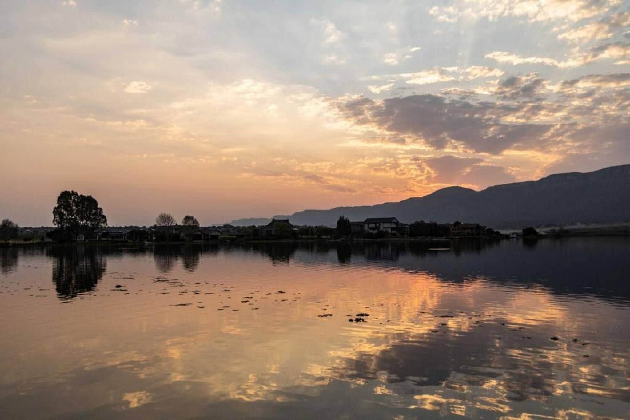 Un lac paisible où le ciel et les montagnes lointaines se reflètent.