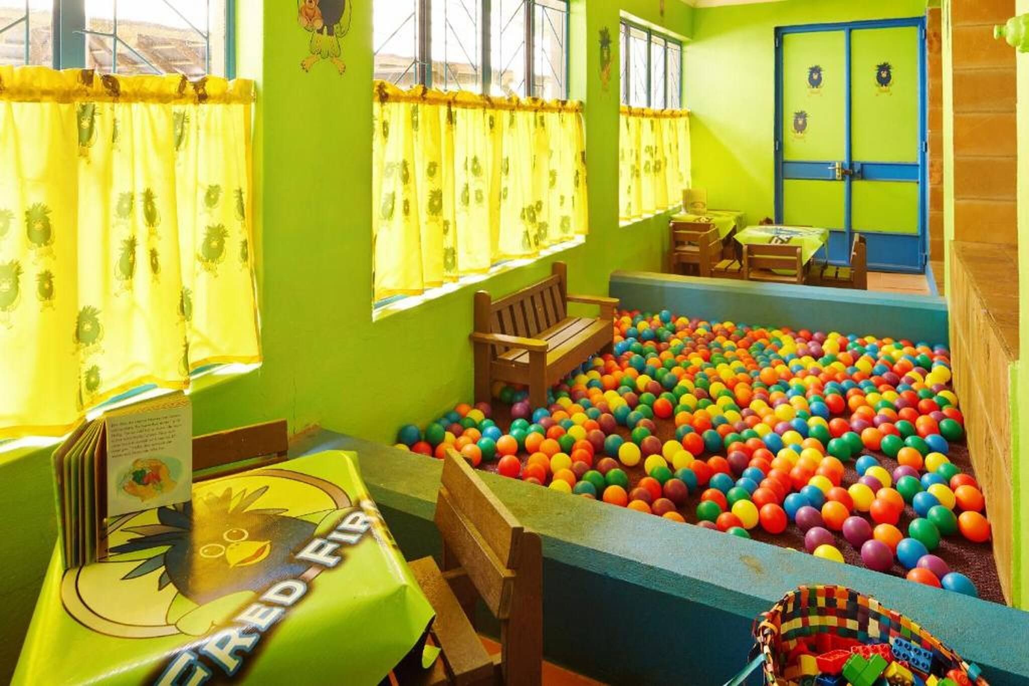 A room with a ball pit, wooden furniture, and a table with a book.