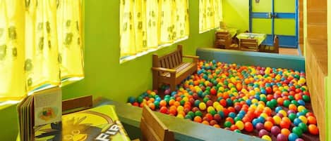Una habitación con piscina de pelotas, muebles de madera y una mesa con un libro.