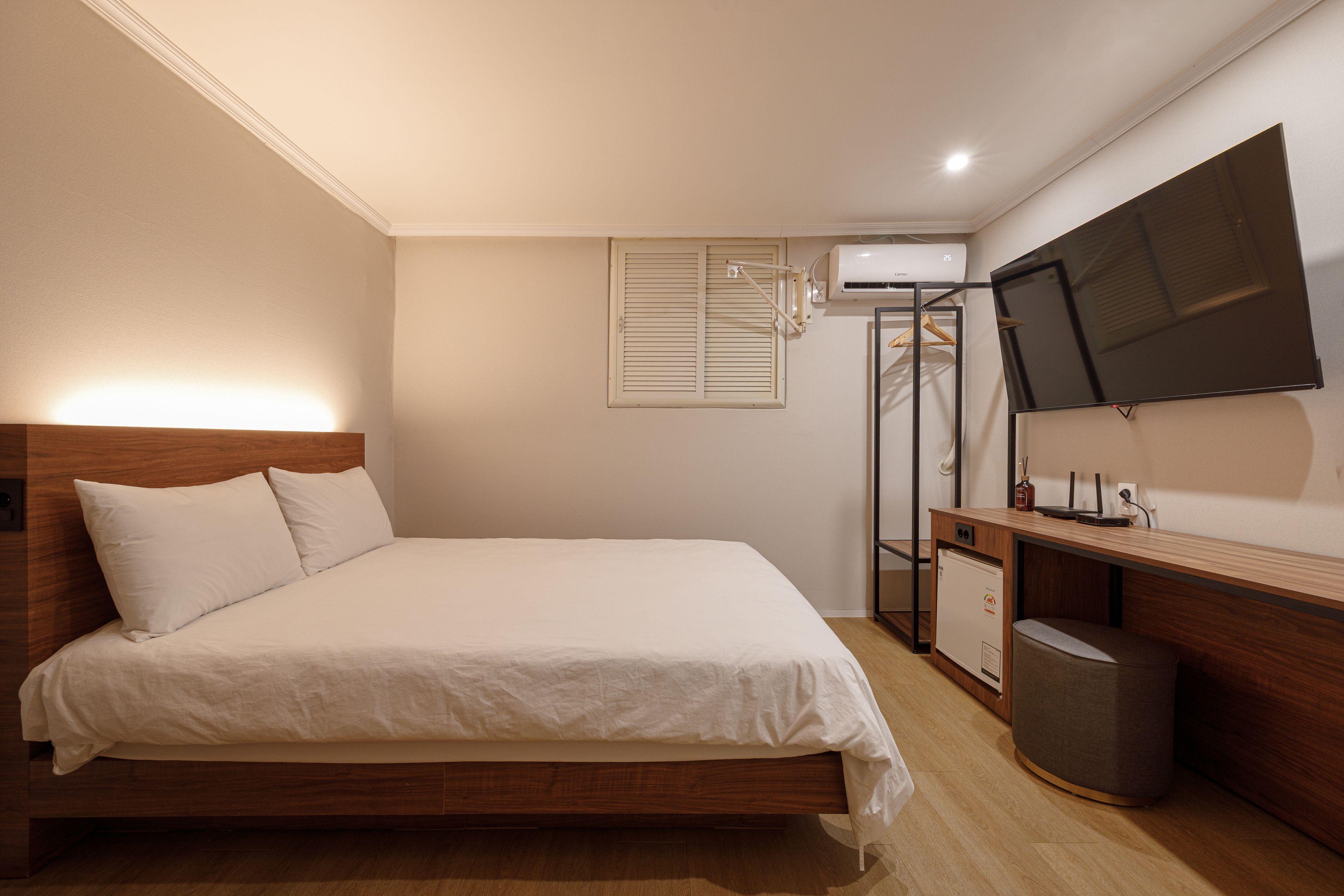 Une chambre à coucher comprenant un lit, un bureau, une télévision et une armoire.