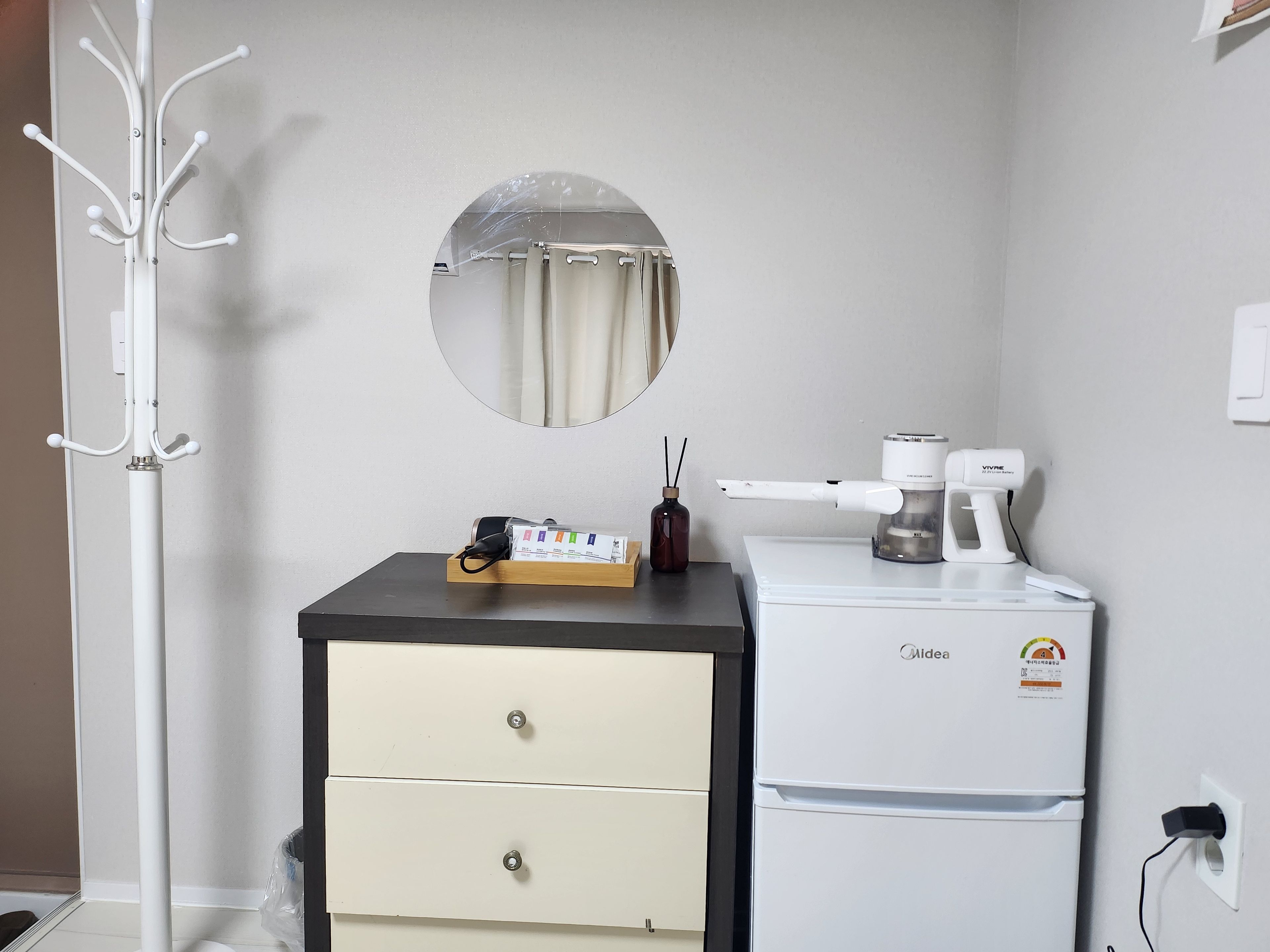 A compact kitchenette with a refrigerator, a coffee maker, and a small cabinet.