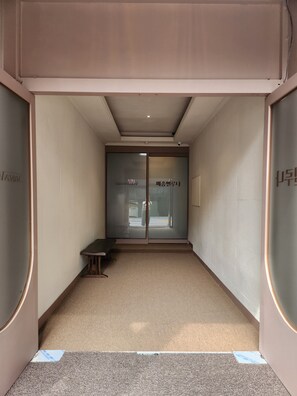A hallway with a bench, double doors with frosted glass, and a ceiling light. - Maison Veluna (Seoul)