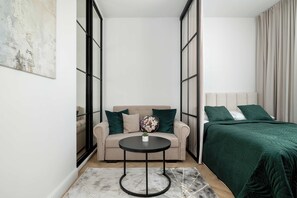 A modern bedroom with a bed, a sofa, and a small table. - Warsaw | Jagiellońska 79 | Stylish Studio | Balcony (Warszawa)