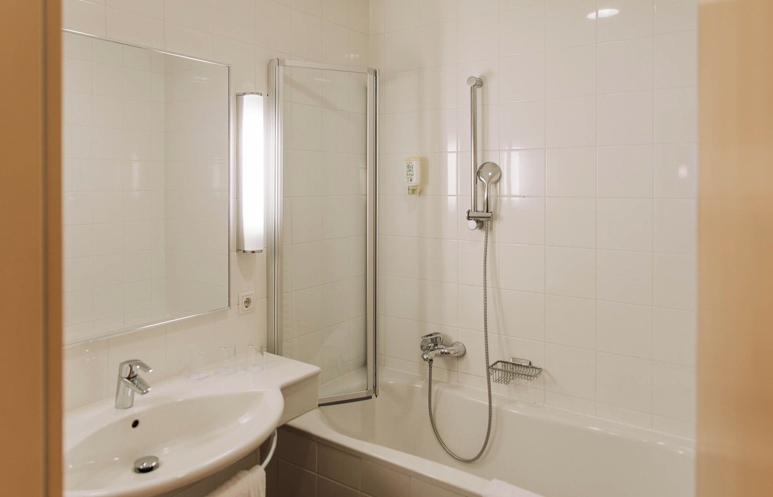 A bathroom with a sink, mirror, and shower.