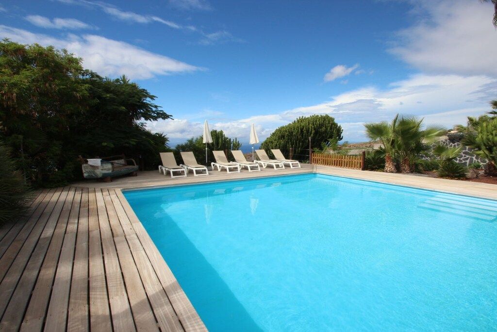 A swimming pool with lounge chairs and a wooden deck.
