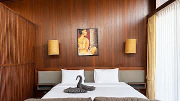 A hotel room with a wooden paneled wall, a bed with white linens, two wall-mounted lamps, and a large woven ceiling light.