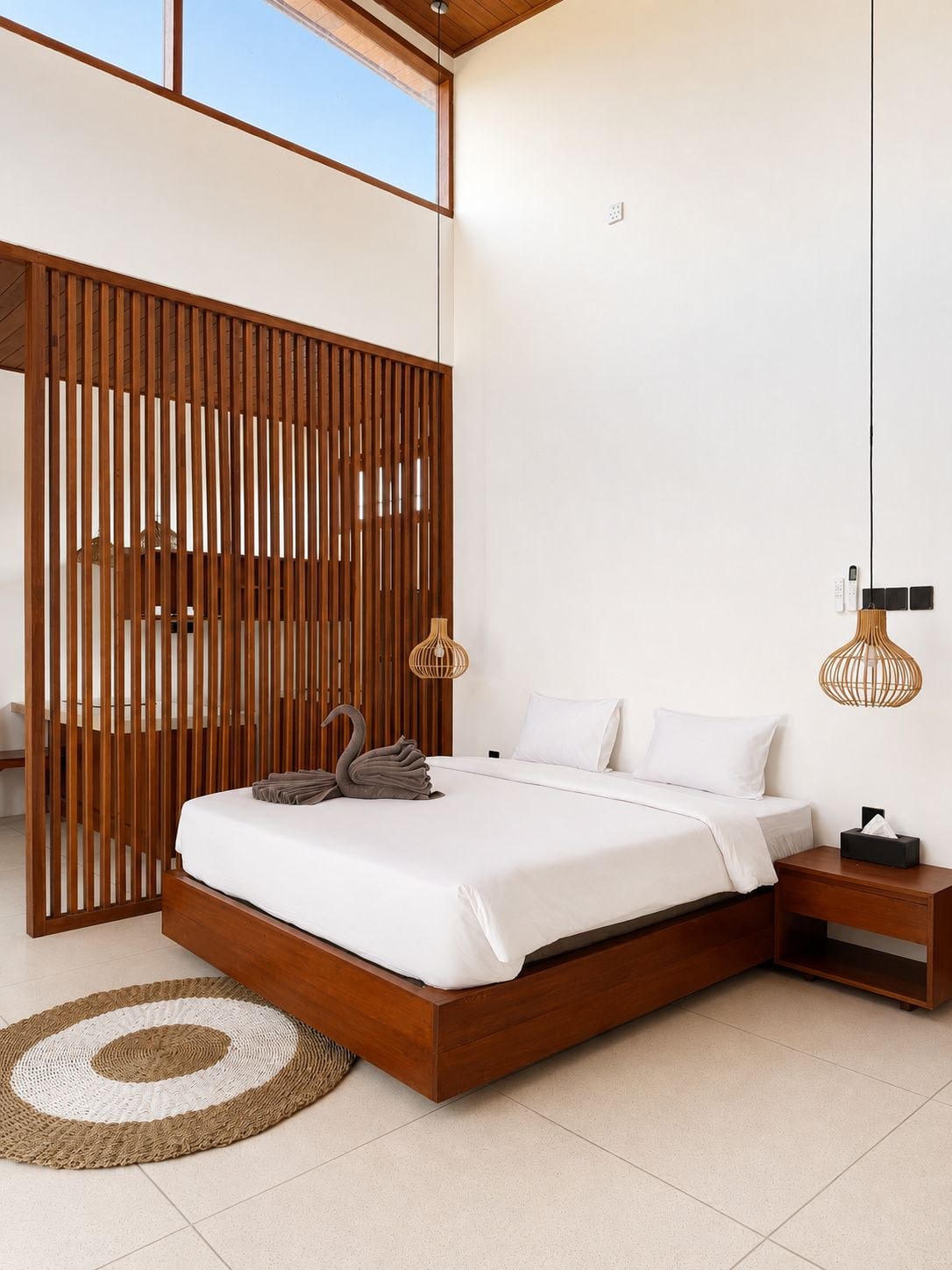 Quarto moderno com estrutura de cama de madeira, tapete redondo tecido e divisória de madeira.
