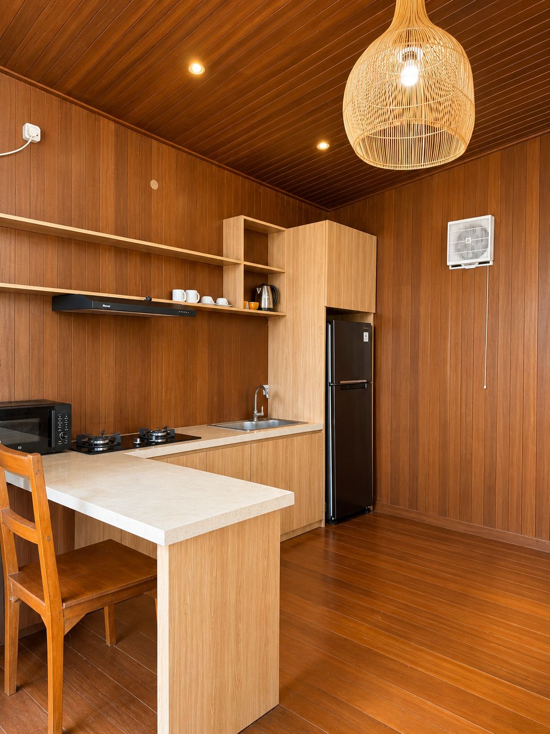 A modern kitchen with wooden paneling, a central island, a built-in microwave, a gas stove, and a black refrigerator.