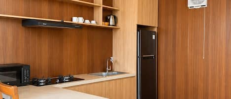 Une cuisine moderne avec un lambris en bois, un îlot central, un four à micro-ondes encastré, une cuisinière à gaz et un réfrigérateur noir.