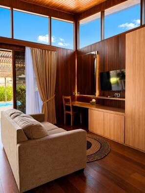 A modern living room with a sofa, a desk, and a television. - Villa Lantis Mawun (Kuta)