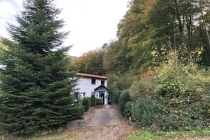 A house with a pathway leading to the entrance, surrounded by dense greenery and trees. - Bruni's holiday apartment (Wachenheim an der Weinstr.)