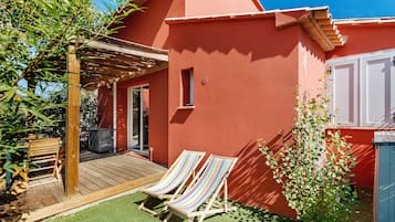 A red building with a wooden deck and two striped lounge chairs.