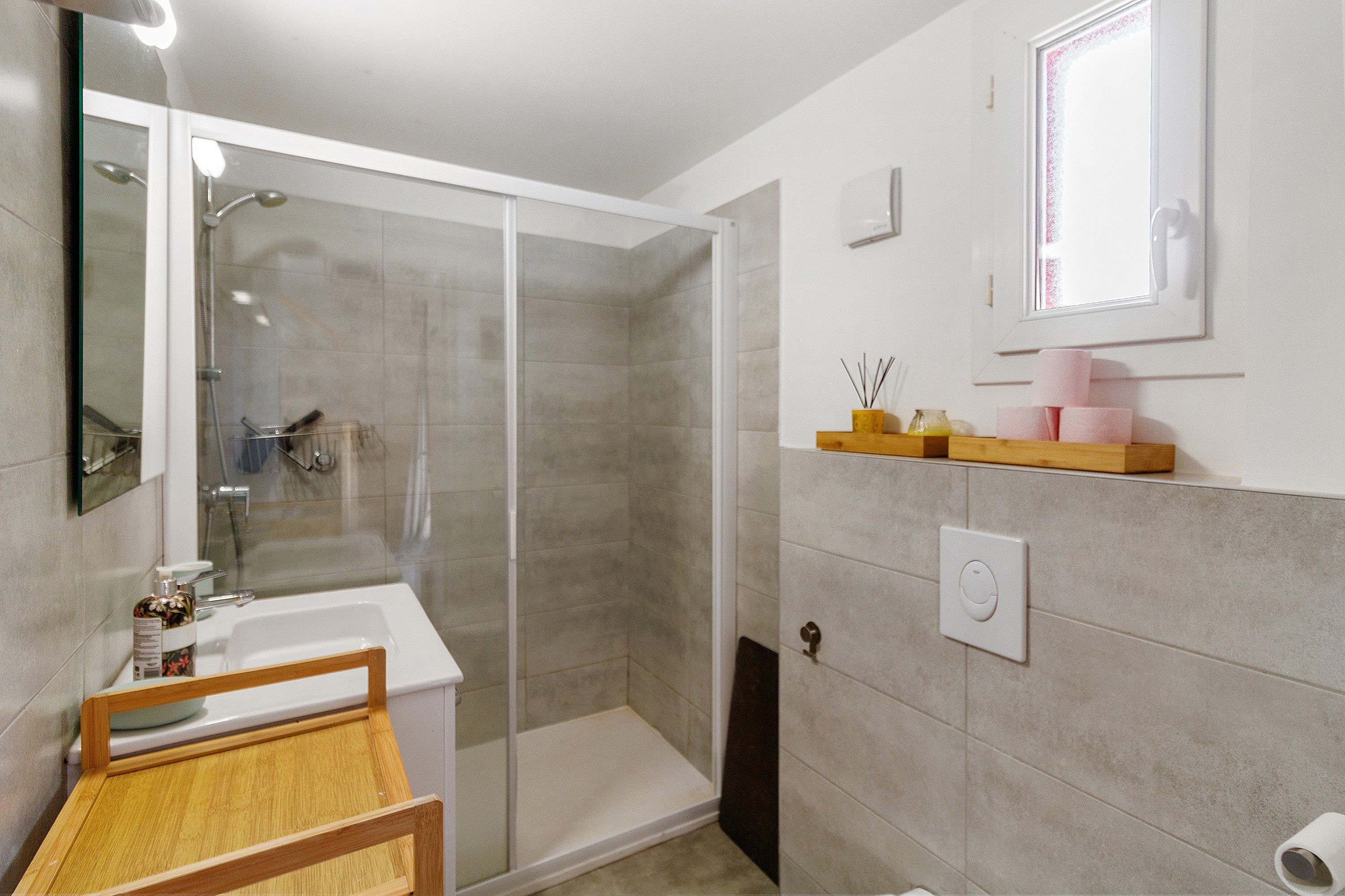Une salle de bain équipée d’une douche, d’un lavabo, d’un miroir et d’un porte-serviettes.