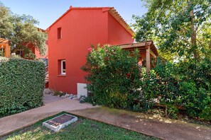 Un bâtiment rouge avec une petite fenêtre et une pergola en bois.