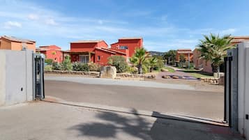 A residential area with red buildings, a paved road, and a clear sky.