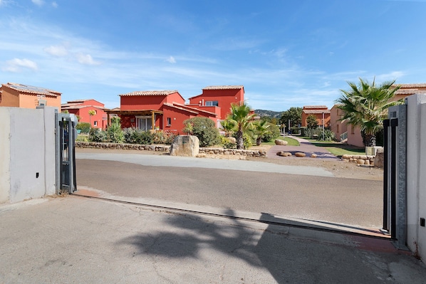 A residential area with red buildings, a paved road, and a clear sky. - Villa Sylody: mountain view, Wi-Fi, air conditioning, near San Ciprianu beach (Lecci)