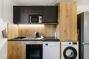A compact kitchen with a microwave, dishwasher, and a washing machine. - Villa Sylody: mountain view, Wi-Fi, air conditioning, near San Ciprianu beach (Lecci)