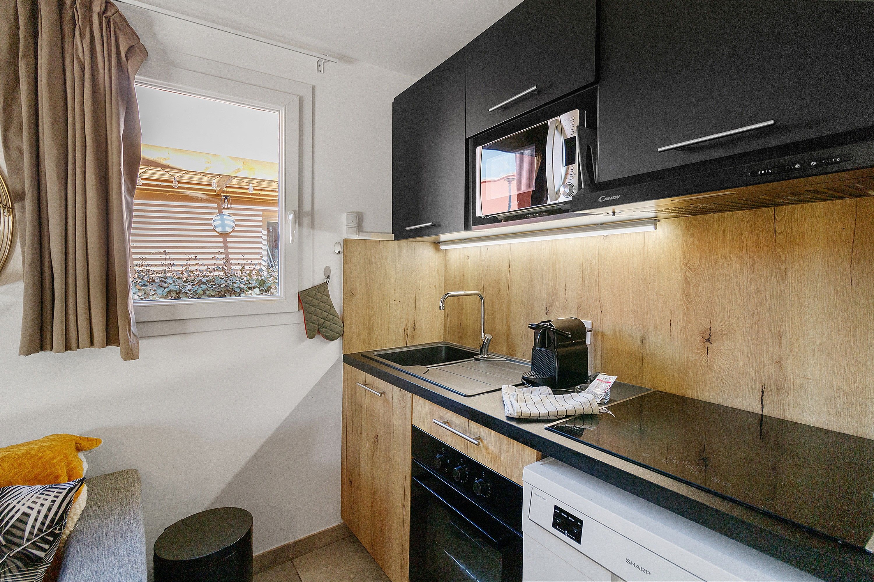 A compact kitchen with a microwave, a coffee maker, and wooden cabinetry.