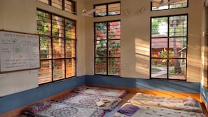 A room with large windows, a whiteboard with notes, and a meditation mat.