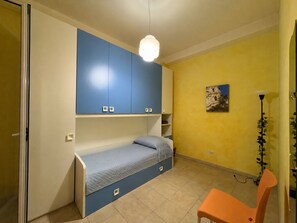 A room with a bed, a chair, a desk, and a hanging light fixture. - Appartamento Il Vulcano (Pozzallo)