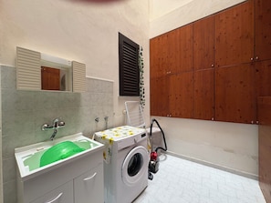 Ein kleines Badezimmer mit Waschbecken, Spiegel und Waschmaschine.