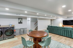A modern living room with a dining area, a washing machine, and a television. - Lake Views, Hot Tub! Chautauqua Family Retreat (Mayville)