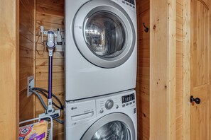 A front-loading washing machine with a control panel, a hose, and a power outlet. - Mammoth Cave Retreat w/ Hot Tub & Game Loft (Mammoth Cave)