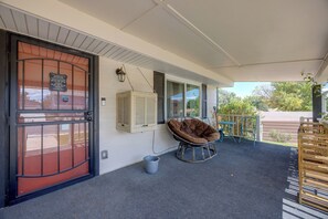 A covered porch with a swing chair, a door with a sign, and a window with shutters.