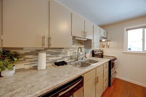 A kitchen with a double sink, a dishwasher, and a stove.