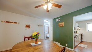A dining area with a wooden table and chairs, a vase with flowers, and a ceiling fan. - Walk to Prospect Lake! Quiet Home w/ Porch (Colorado Springs)