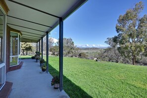 A covered outdoor area with a view of a grassy landscape and distant mountains.