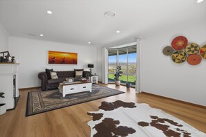 A spacious living room with a large window, a sofa, a coffee table, and a cowhide rug.