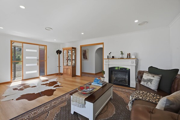 A spacious living room with a fireplace, a leather sofa, a coffee table, and a cowhide rug.