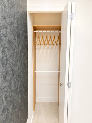 Ein begehbarer Kleiderschrank mit Holzgalgen und einer weißen Tür.