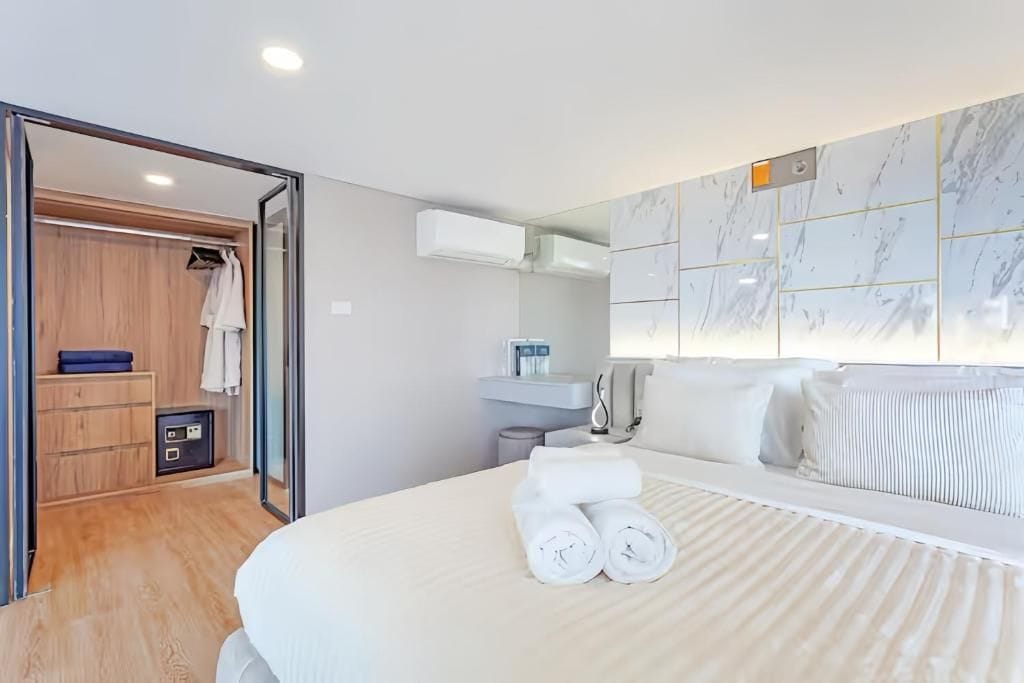 A hotel room with a bed, a bathroom, a wardrobe, and a mirror.