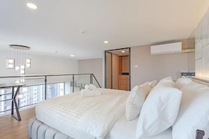 A modern bedroom with a large bed, a desk, and a balcony. - Cassia Residence Rama 9 Bangkok (Krung Thep Maha Nakhon)