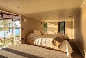 Une chambre dotée d’un grand lit, offrant une vue sur l’extérieur et donnant accès à un balcon par une porte coulissante.