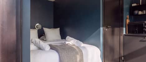 Quarto com cama, mesa de cabeceira, espelho e guarda-roupa.