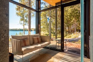 A modern interior with a sofa facing a glass door leading to a deck.