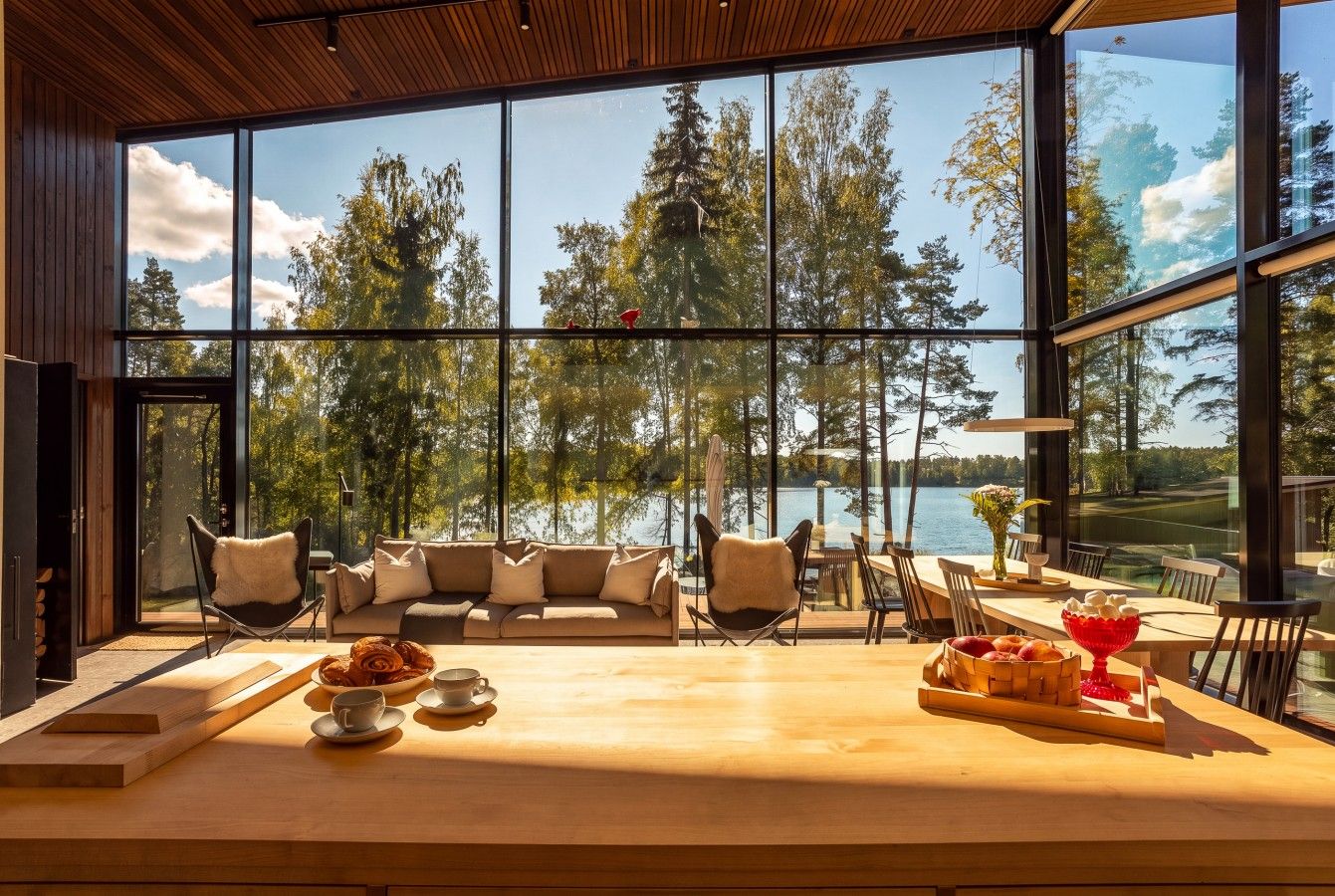 Een modern interieur met een groot raam met uitzicht op een bos en meer.