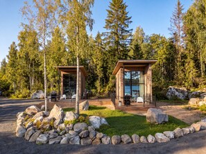 Une cabane dotée d’une façade en verre, entourée d’un paysage naturel composé d’arbres et de rochers.