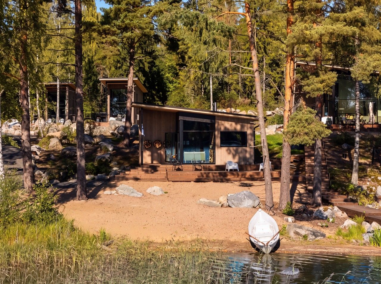 Une cabane aux murs en bois, entourée d’arbres et bordée d’un petit étang.
