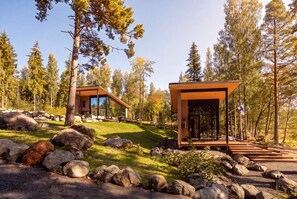 A modern cabin with a glass facade, surrounded by a natural landscape with rocks and trees. - Stay North - Vuohilahti (Valkeakoski)