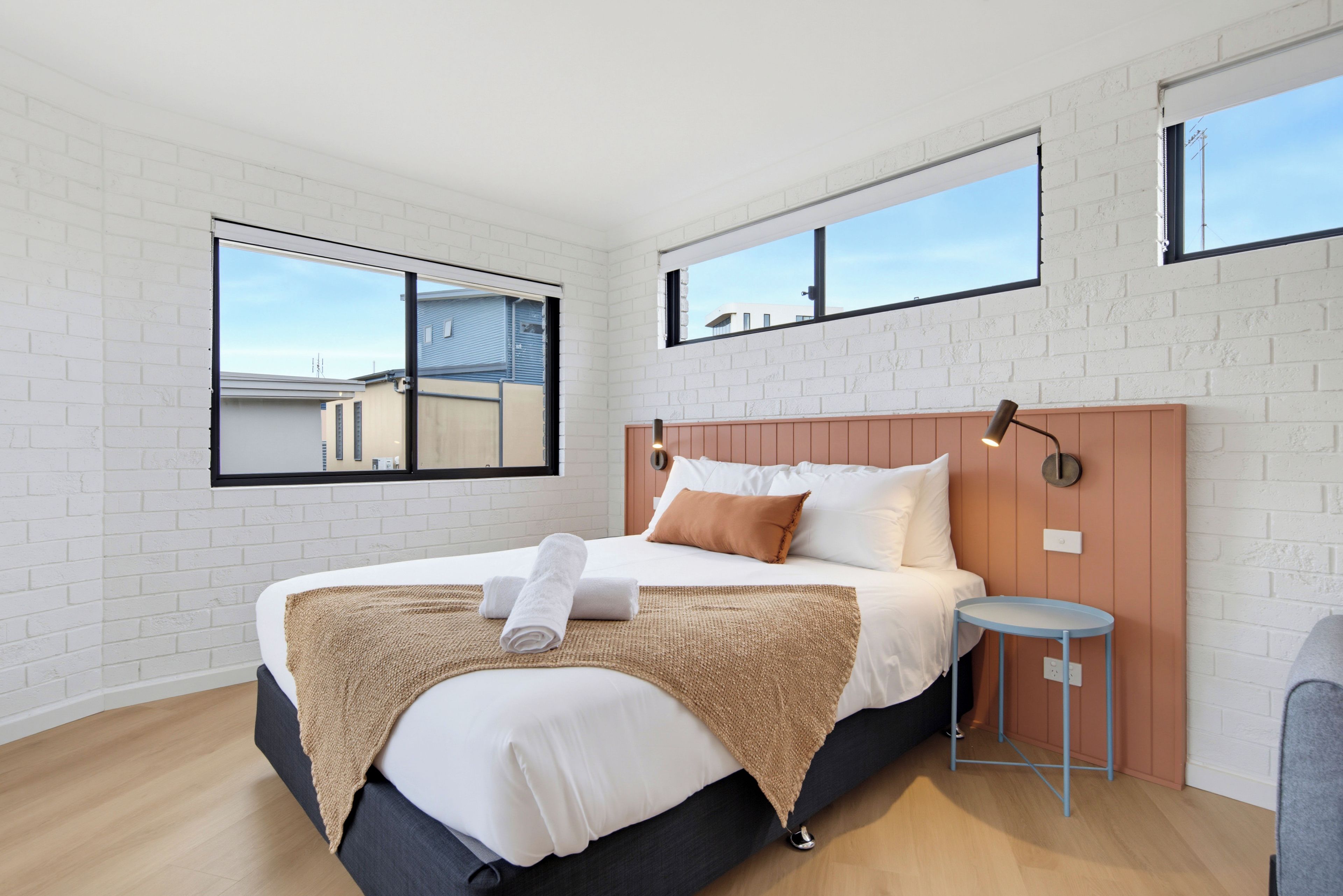 Un dormitorio moderno con una cama grande, una mesita de noche y una ventana.